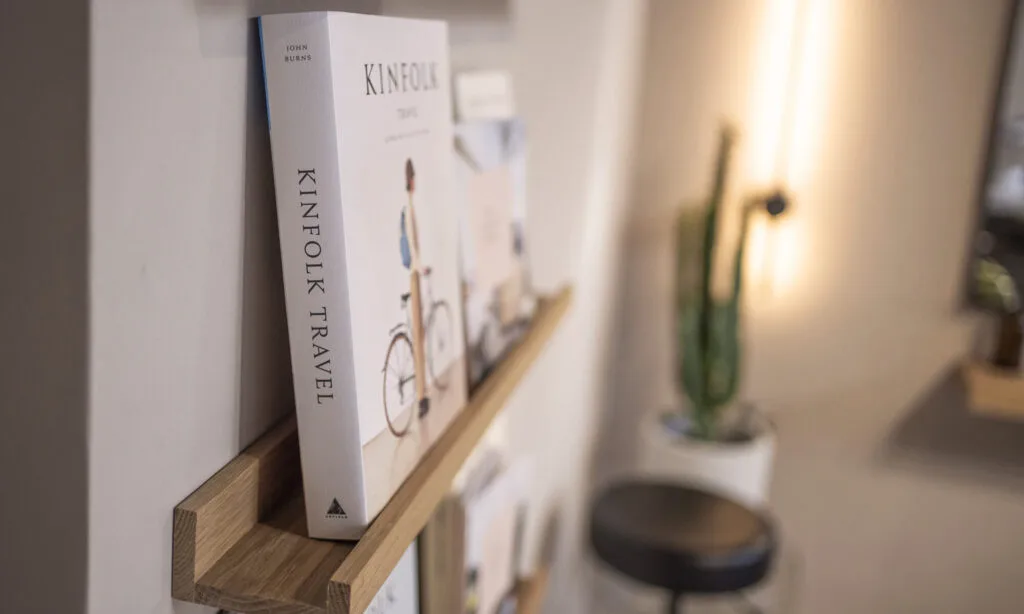 4 mosu-hair-space-kinfolk-bookshelf-interior-detail - Mosu Hair Space Kinfolk travel book displayed on oak shelf inside mosu hair space